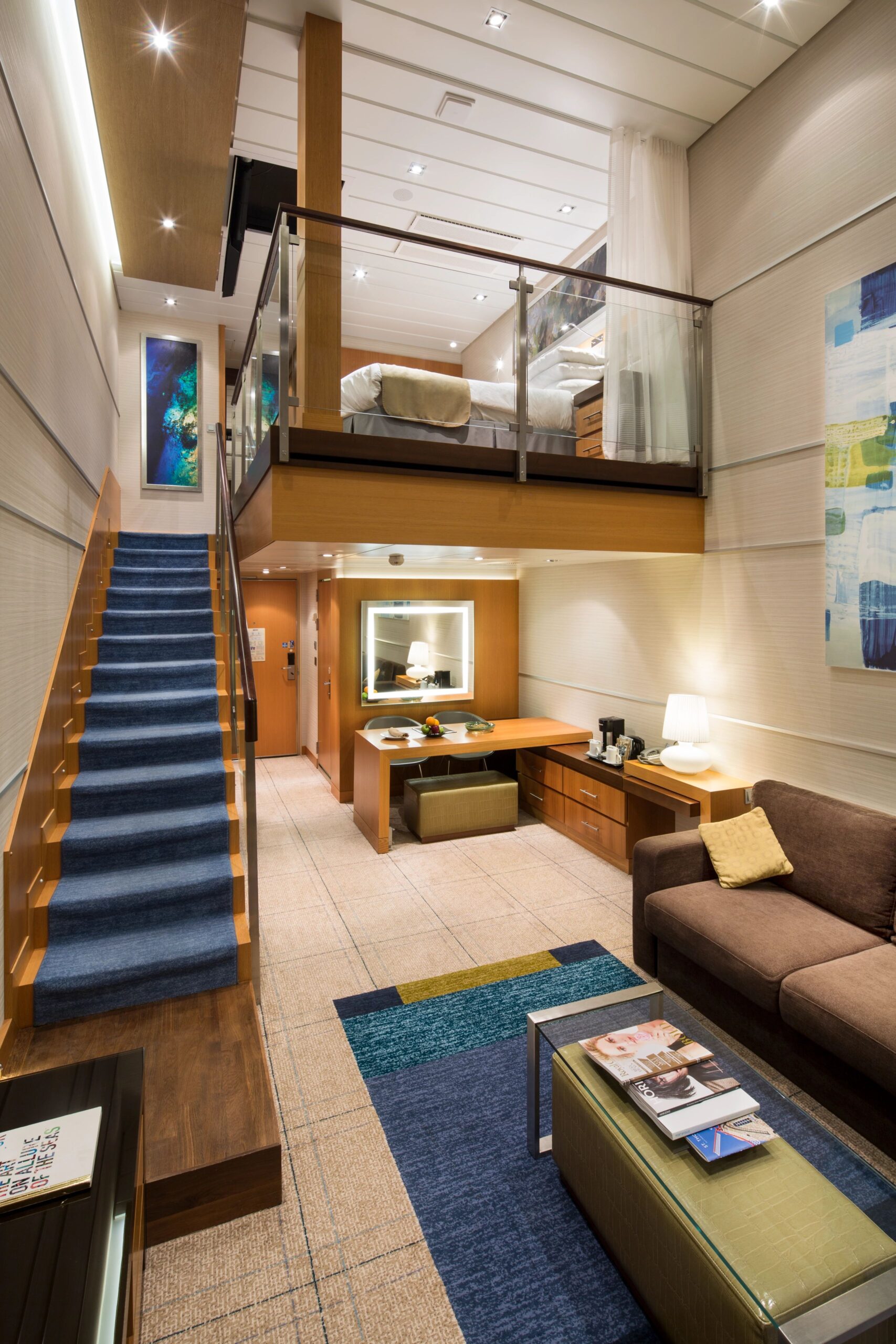 "Modern two-story living room area in a Royal Caribbean Star Class suite featuring a spiral staircase and ocean views."
